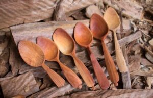 Flera handtäljda träskedar ligger på ved och bark